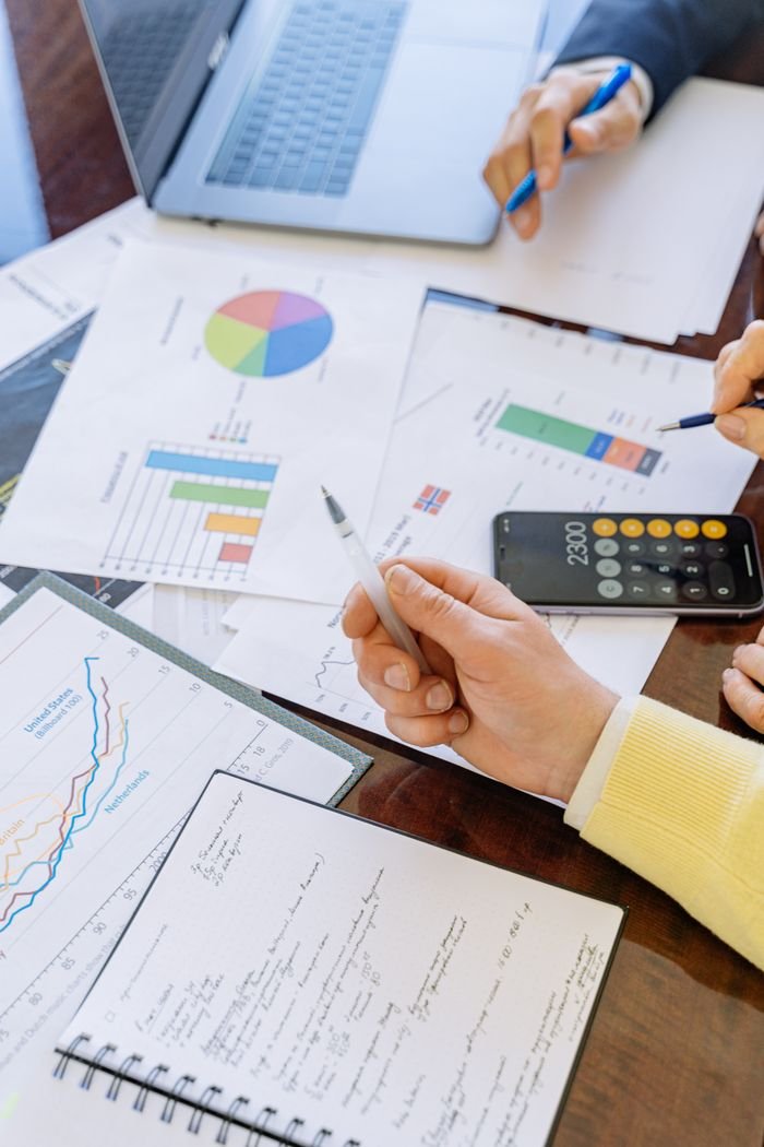 Menu A close-up of businesspeople analyzing financial data and charts during a meeting.