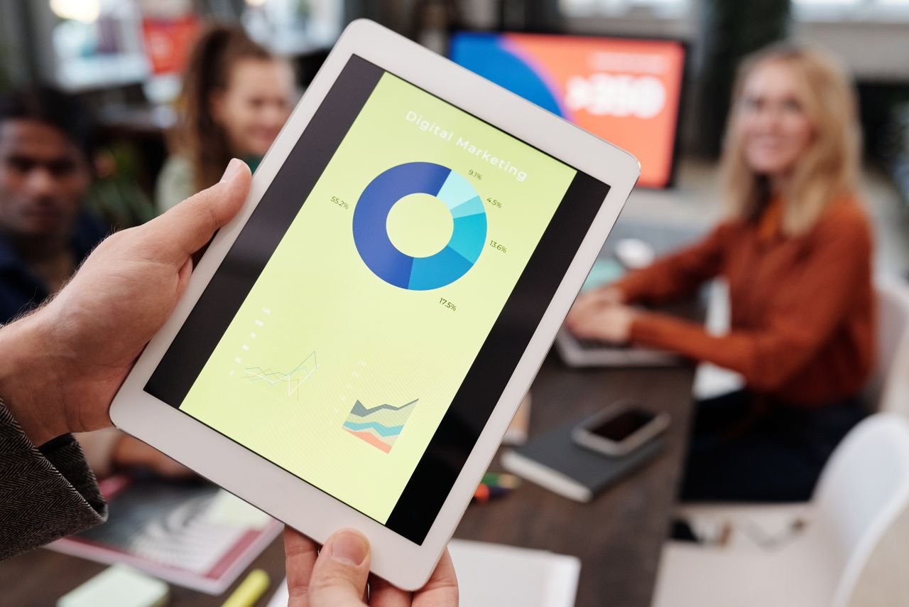 Menu Business team reviewing digital marketing statistics on a tablet during an indoor meeting.